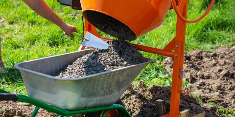 Bétonnière dont la cuve basculante remplit une brouette avec du béton