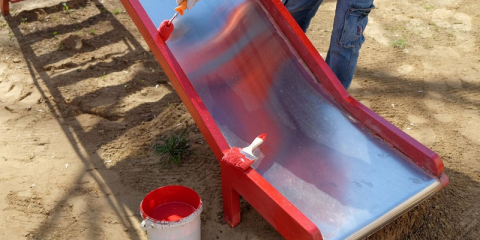 Application de peinture sur un toboggan en bois